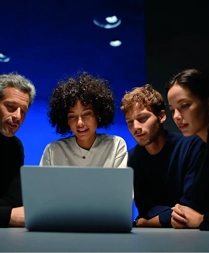 Equipe reunida em frente a um notebook, analisando resultados de performance em ambiente corporativo moderno com iluminação azul
